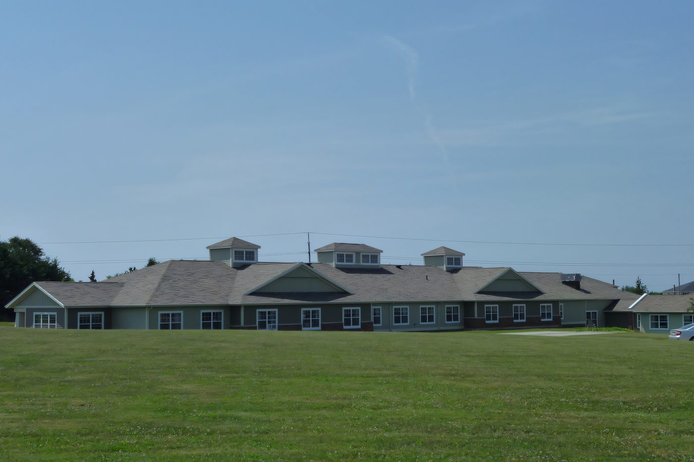 A long single-storey seniors' complex with three dormers, seen across a wide lawn