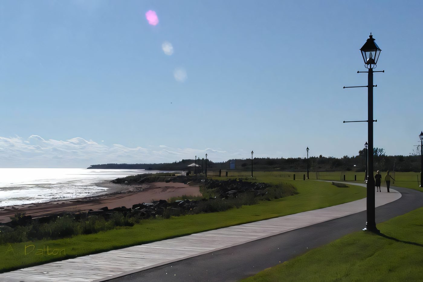 A wooden boardwalk with lamp posts running along the red shoreline in Summerside, the water on the left