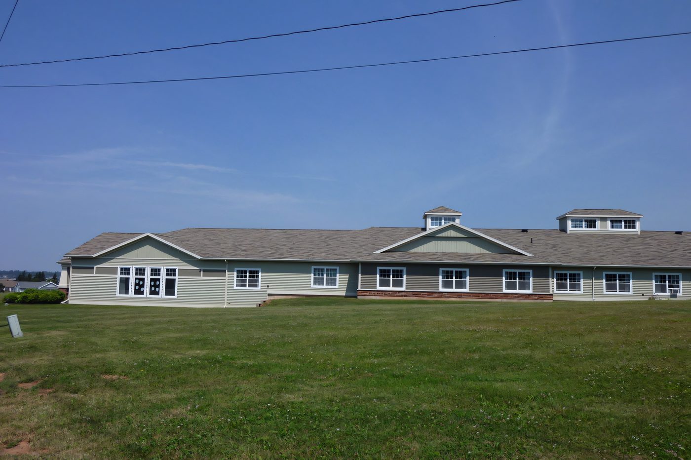 A long single-storey seniors' complex with dormers and a lawn, photographed on a clear day