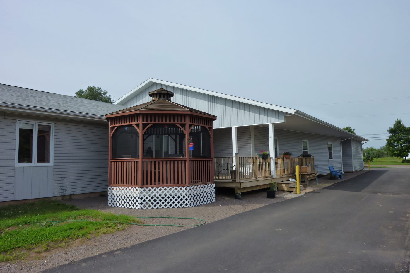 A small pavilion with a gazebo and a covered porch beside a low residential building