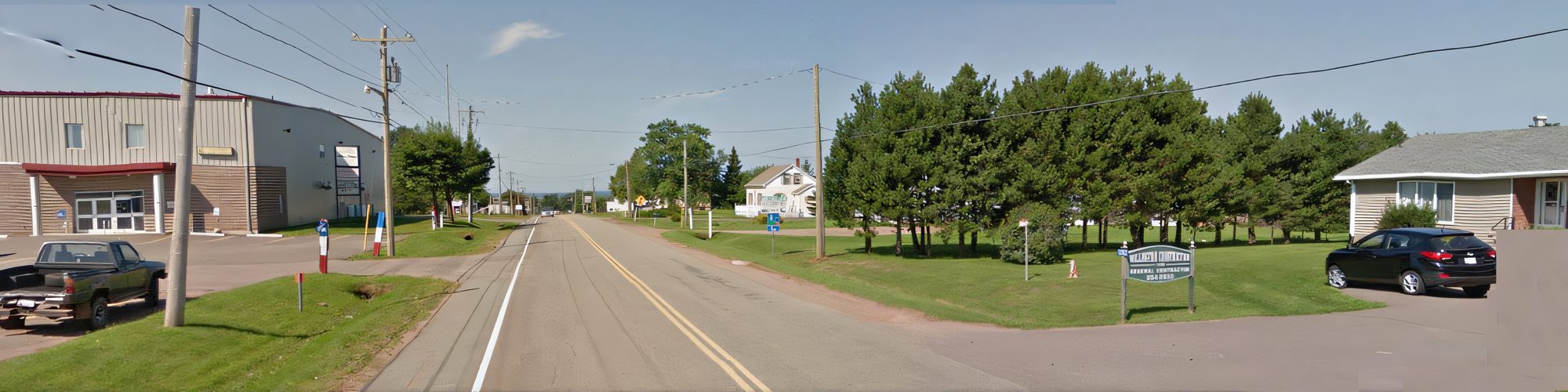 Route 124 running past the company's yard and office in Wellington, a pickup truck and a steel building on the left