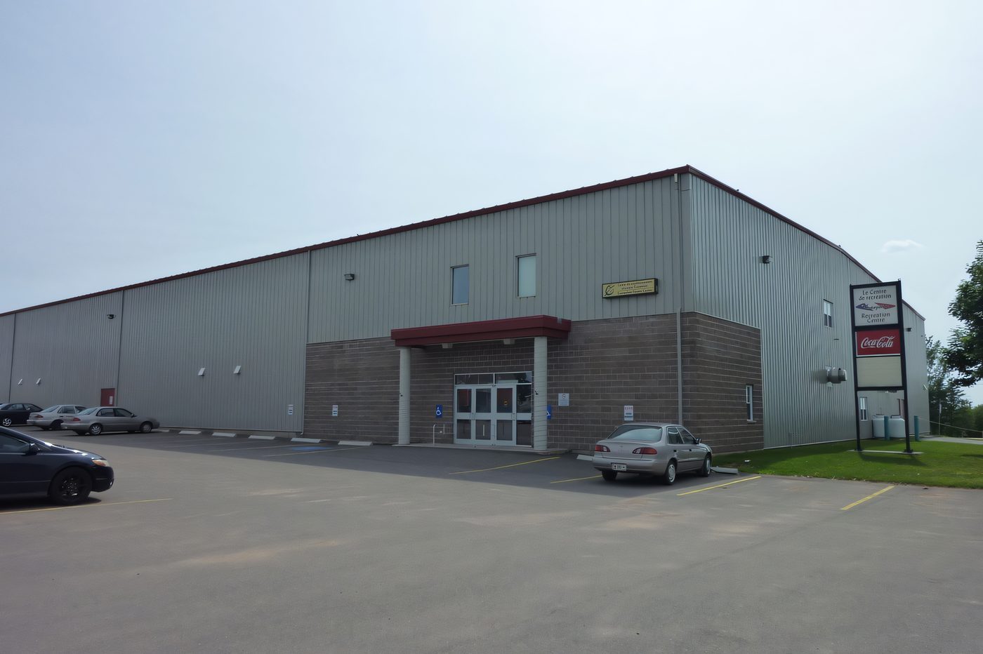A grey pre-engineered steel building with a block base and a covered entrance, under a wide sky